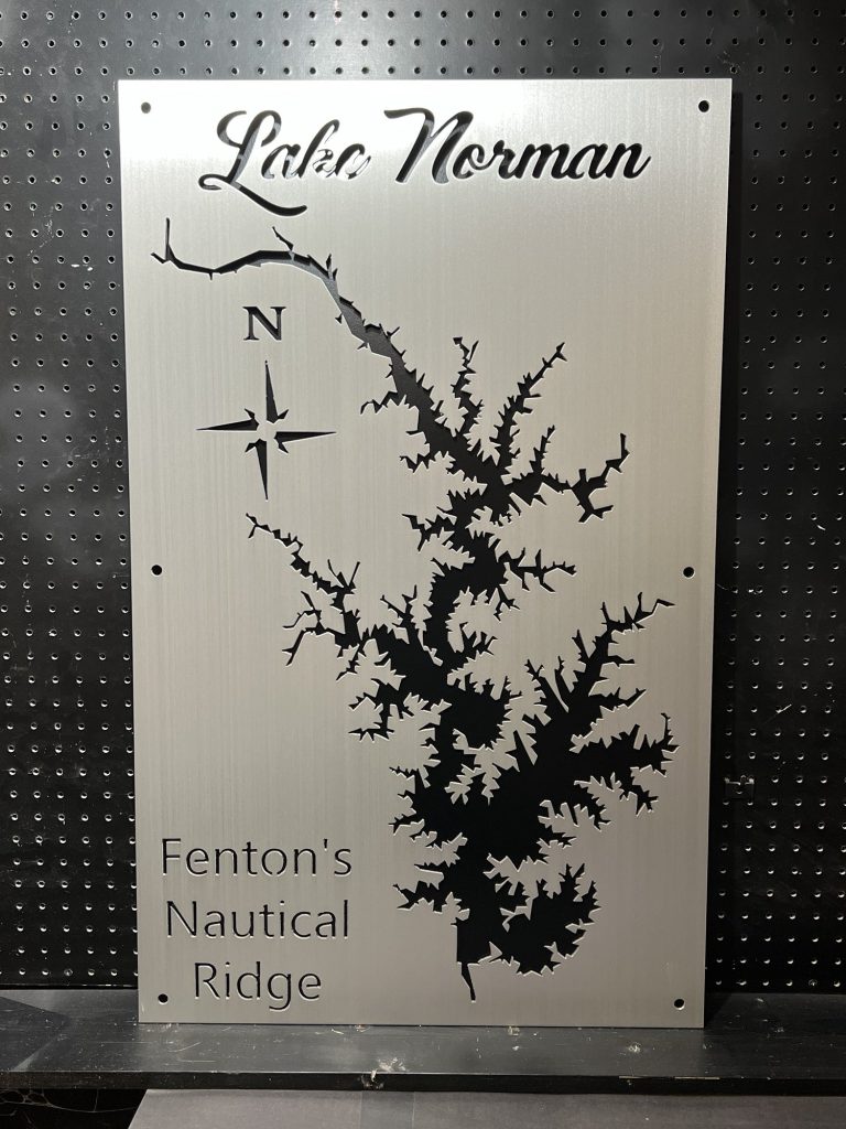 Lake Norman custom metal map with "Fenton's Nautical Ridge" text and compass rose, displayed on a dark pegboard.