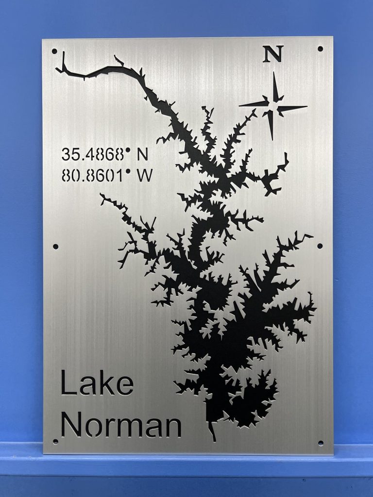 Lake Norman metal map with coordinates and compass rose, displayed on a blue wall.