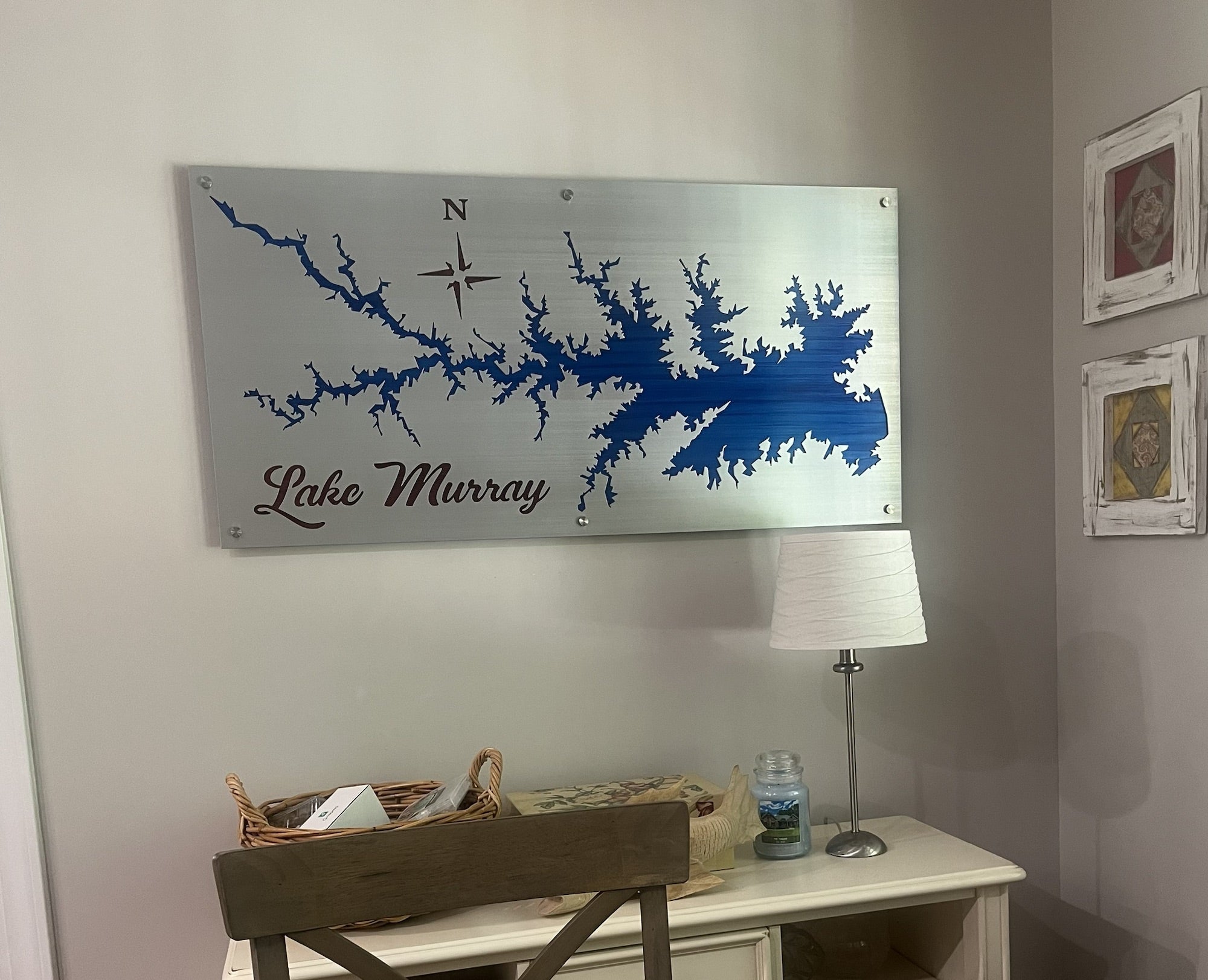 Lake Murray metal map with compass rose, mounted above a desk with a lamp and basket in a cozy room.