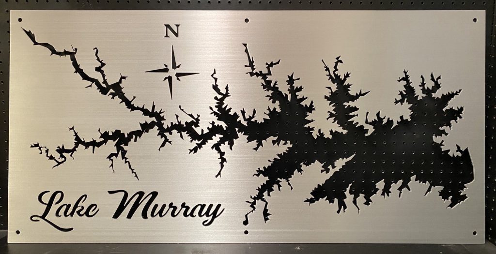 Lake Murray black cutout metal sign with compass rose, mounted on a perforated black background.