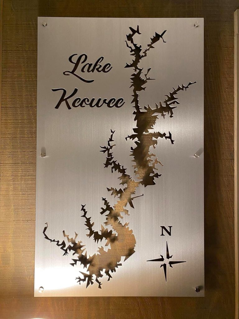 Lake Keowee custom metal map with intricate cutout and compass rose on a wooden wall.