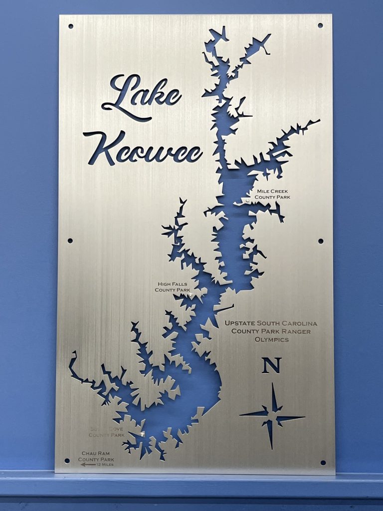 Lake Keowee metal map with park names and compass rose on a brushed metallic background.