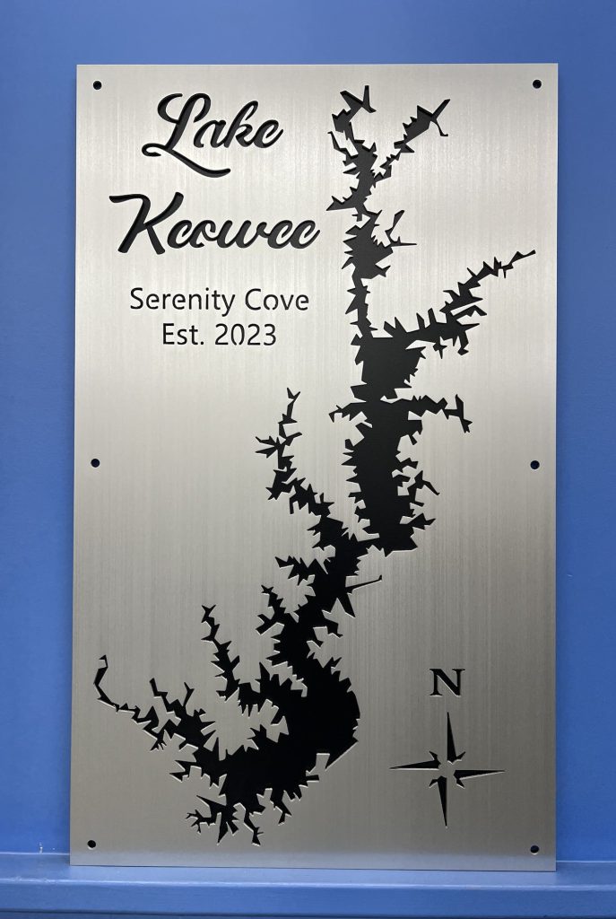 Lake Keowee metal map with "Serenity Cove, Est. 2023" text and compass rose on a brushed metal background.