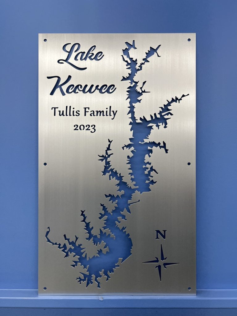 Lake Keowee metal sign featuring "Tullis Family 2023" with compass rose, mounted on a blue wall.