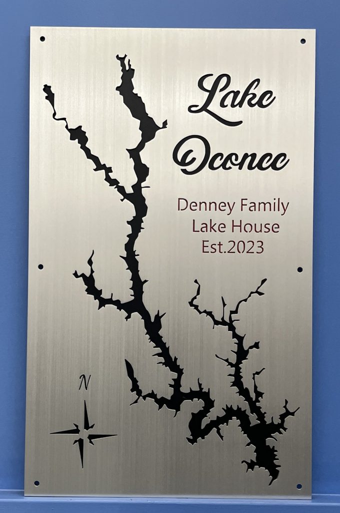 Lake Oconee map with "Denney Family Lake House Est. 2023" text and compass rose, on a brushed silver background.