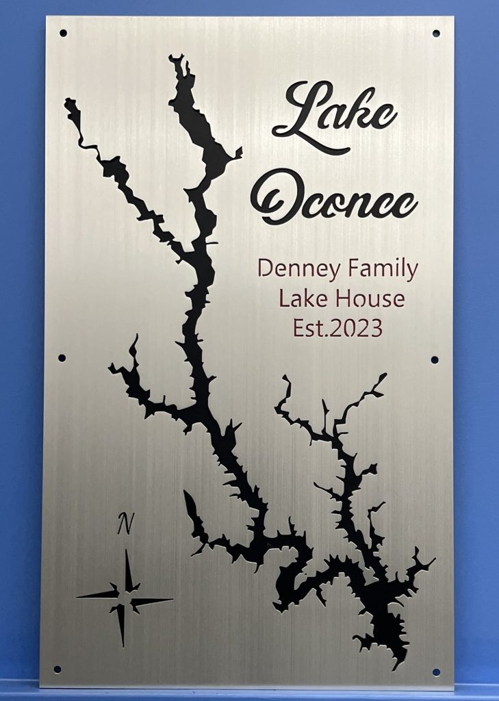 Lake Oconee custom map sign with "Denney Family Lake House Est. 2023" text and compass rose on brushed metal.