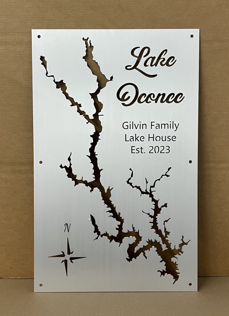 Lake Oconee map with "Gilvin Family Lake House Est. 2023" text and compass rose on brushed metal.