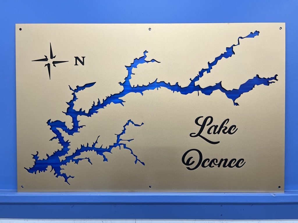 Lake Oconee custom metal map with compass rose on a blue wall.