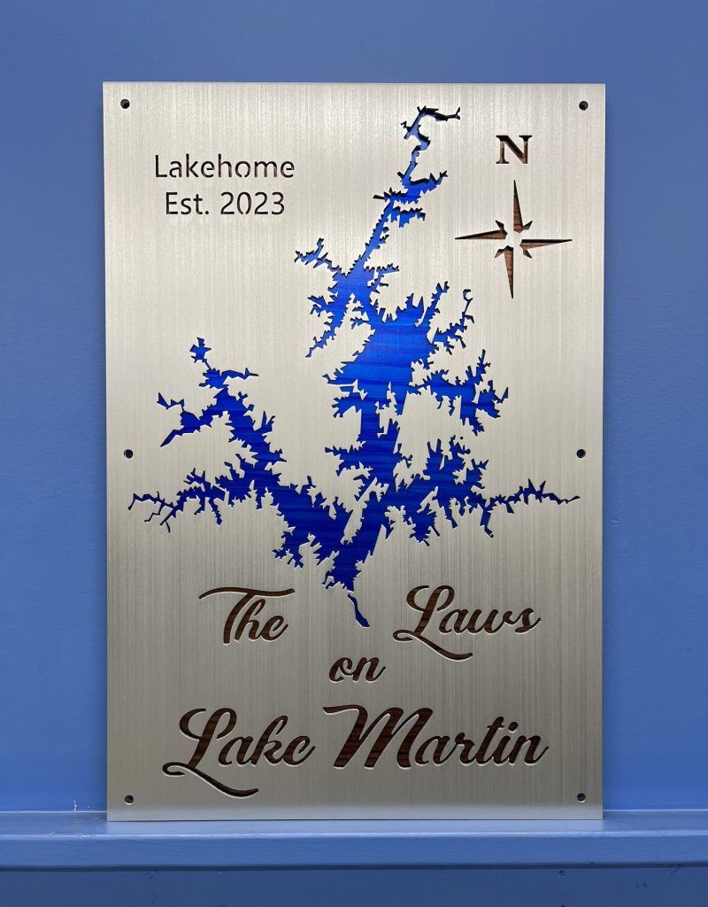 Custom Lake Martin metal sign with compass rose, "The Laws on Lake Martin, Lakehome Est. 2023," mounted on a blue wall.