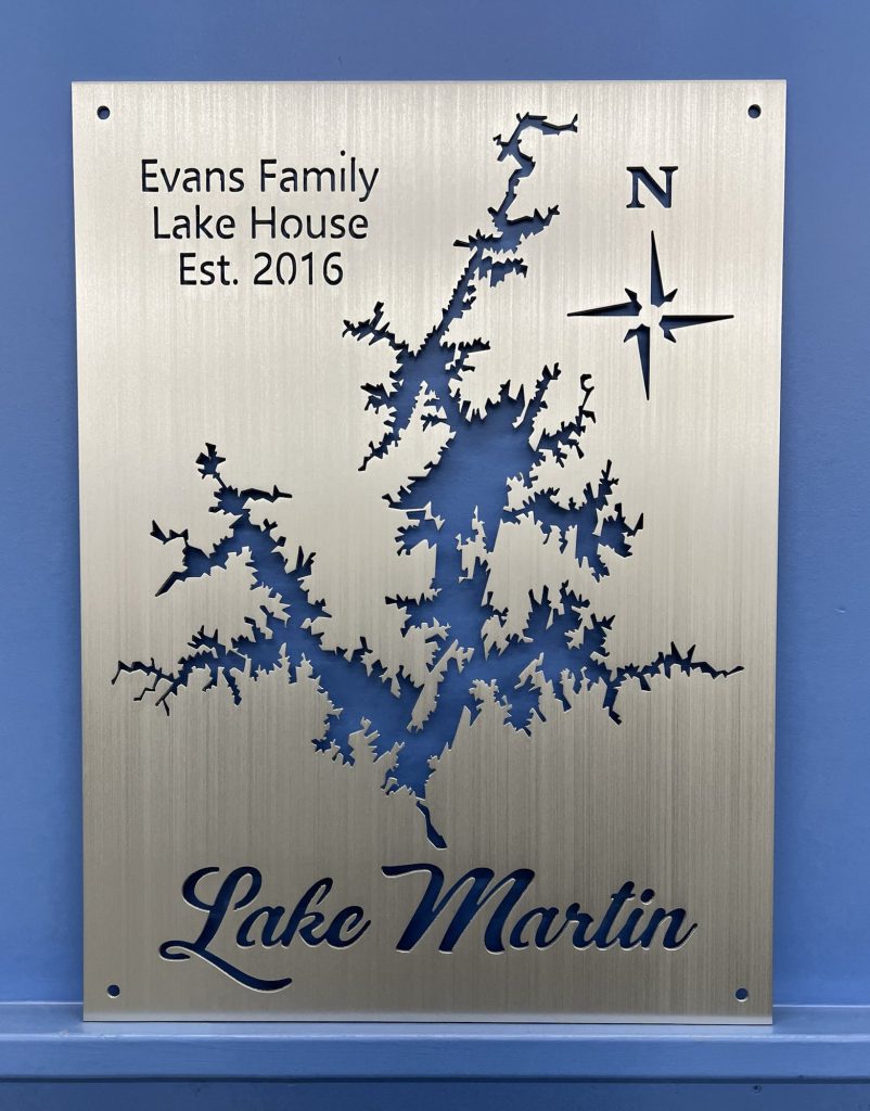 Evans Family Lake House, Est. 2016, Lake Martin map with compass rose on brushed metal, mounted on a blue wall.