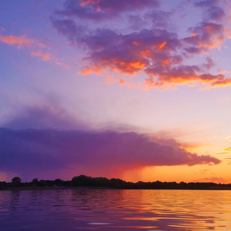 Sunset over water with purple clouds and orange sky.